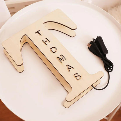 Engraved wooden name sign lamp, unlit, on a table with USB cable