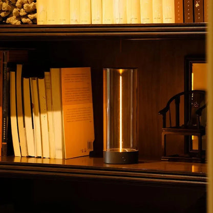 Minimalist Column Table Lamp lit on a bookshelf